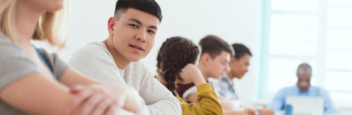Portrait of high school teenage asian student with classmates and teacher sitting in classroom